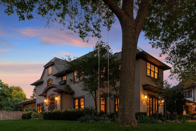 property exterior at dusk featuring a lawn