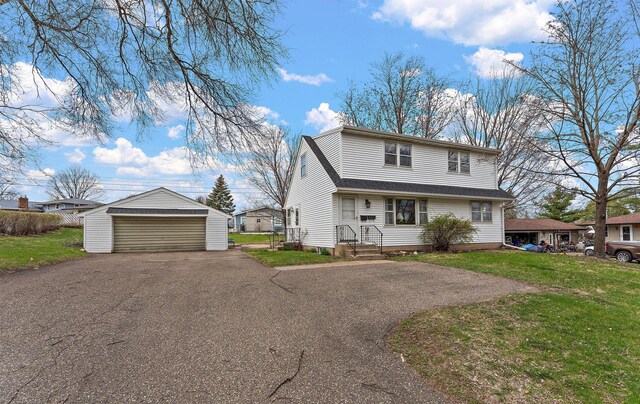traditional-style house featuring a detached garage, an outbuilding, and a front lawn