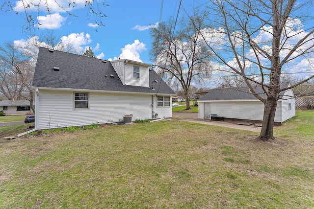 rear view of property with a lawn, central AC unit, a shingled roof, and a patio
