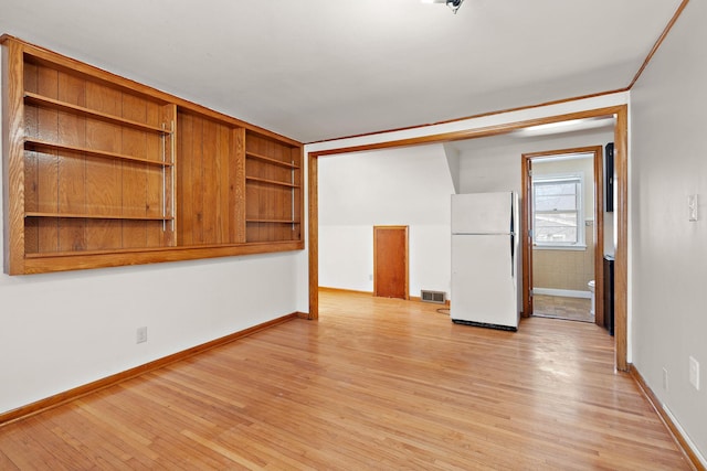 spare room featuring baseboards, visible vents, and light wood finished floors