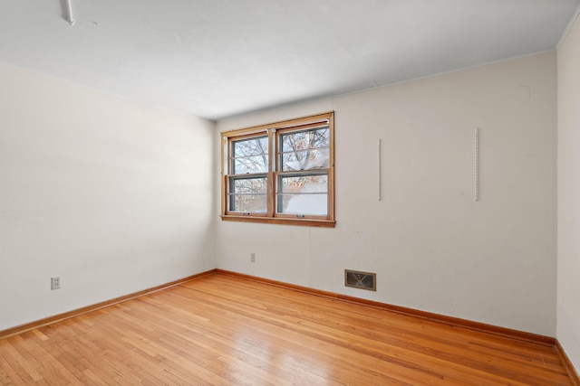 empty room featuring visible vents, light wood-style flooring, and baseboards