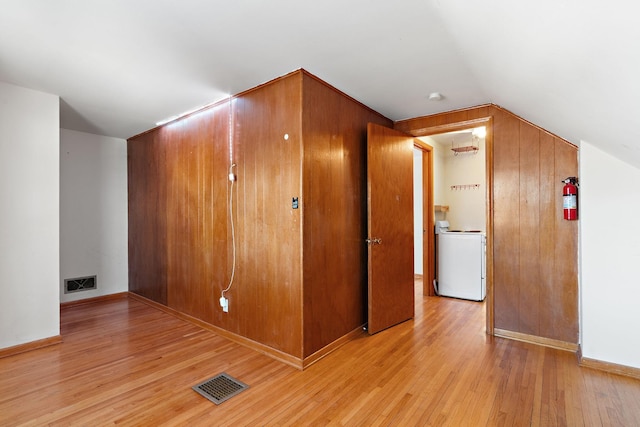 additional living space with washer / clothes dryer, vaulted ceiling, visible vents, and light wood finished floors
