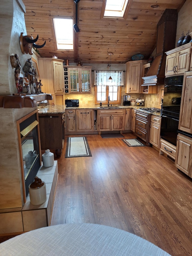 kitchen featuring vaulted ceiling with skylight, decorative light fixtures, a sink, dark wood-style floors, and glass insert cabinets