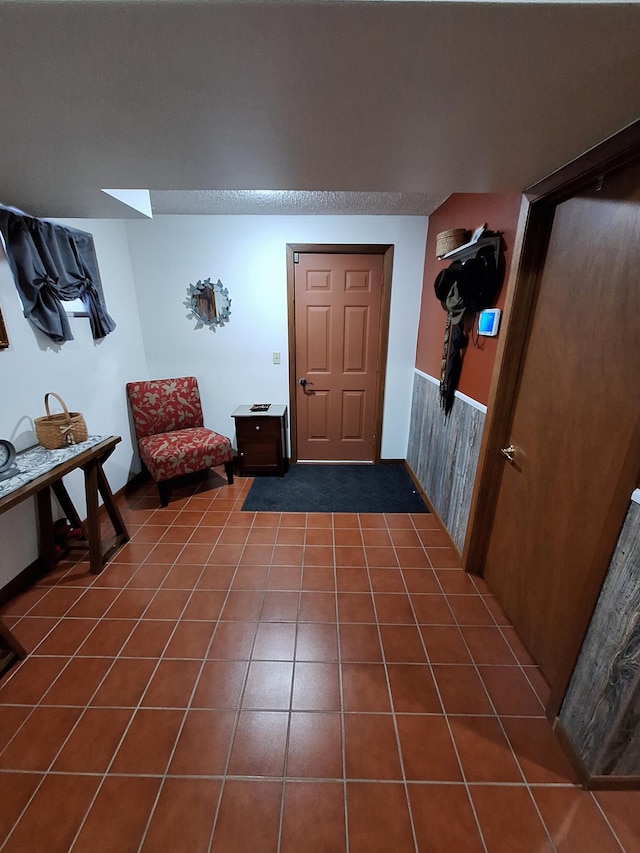 interior space featuring a wainscoted wall, dark tile patterned floors, and a skylight