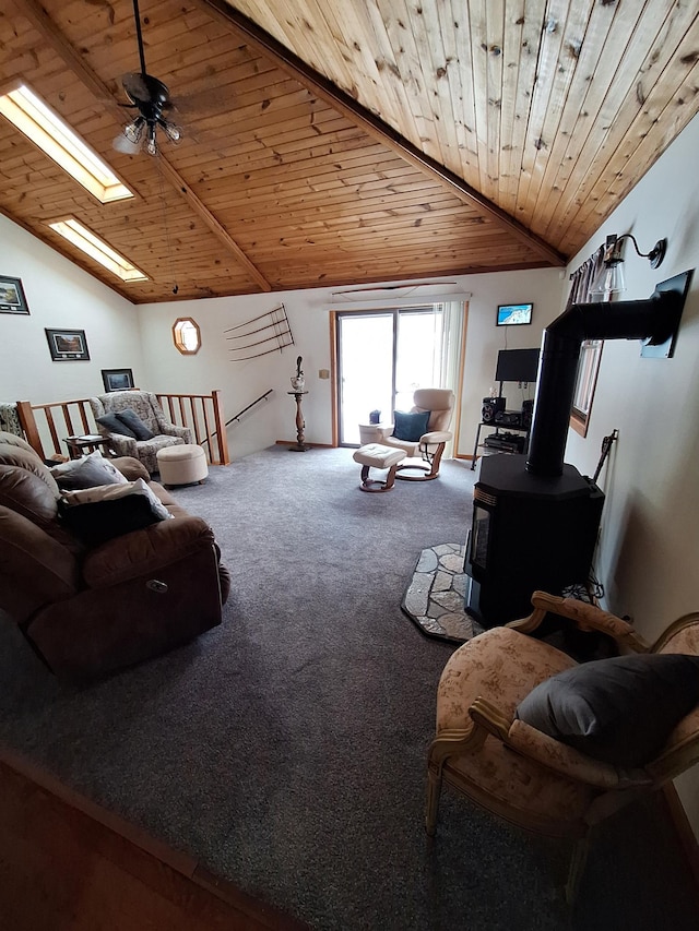 carpeted living room with a wood stove, lofted ceiling with skylight, and wood ceiling