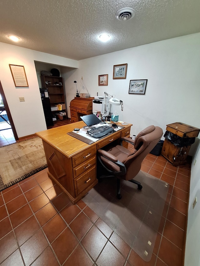 home office with baseboards, dark tile patterned floors, visible vents, and a textured ceiling