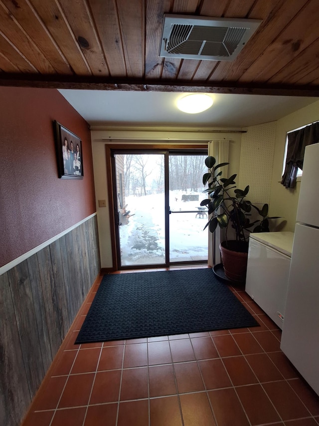 entryway featuring wood ceiling, dark tile patterned floors, and visible vents