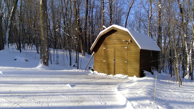 snow covered structure with an outbuilding and a storage shed