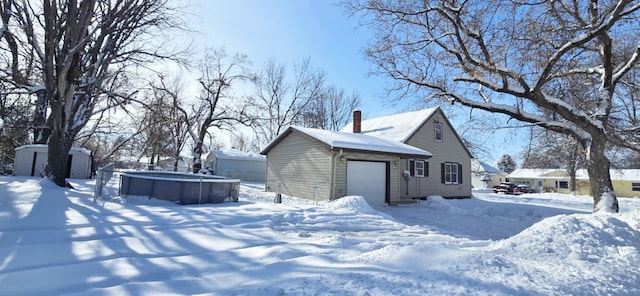 view of snow covered exterior with a garage and a storage shed