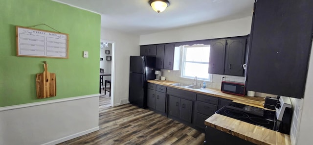 kitchen with sink, black fridge, dark hardwood / wood-style floors, stainless steel electric stove, and backsplash