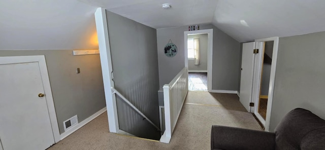 corridor with vaulted ceiling and light carpet