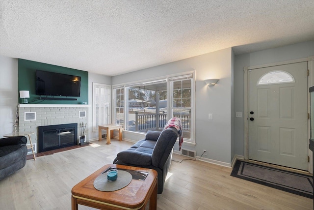 living room featuring a fireplace, light hardwood / wood-style flooring, and a textured ceiling