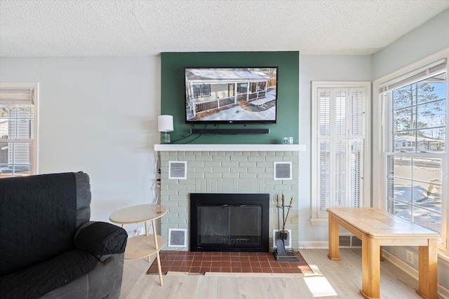 sitting room featuring hardwood / wood-style floors, a textured ceiling, and a brick fireplace