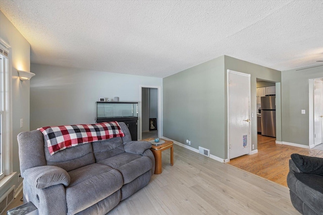 living room with a textured ceiling and light hardwood / wood-style flooring