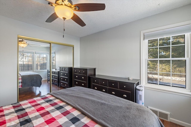 bedroom with dark hardwood / wood-style flooring, ceiling fan, a textured ceiling, and a closet