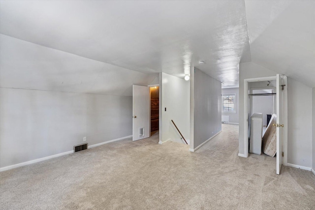 additional living space featuring lofted ceiling and light carpet