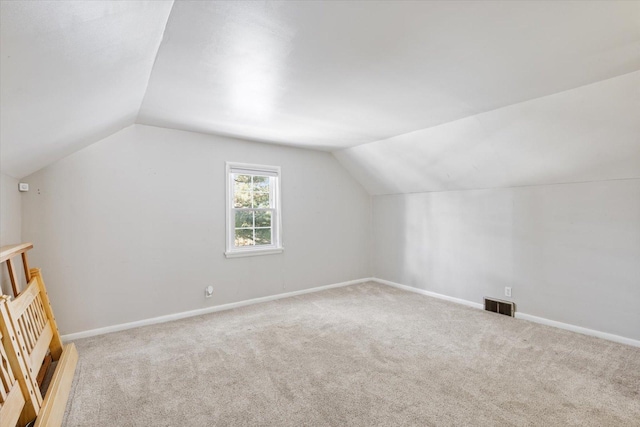 bonus room with lofted ceiling and light carpet