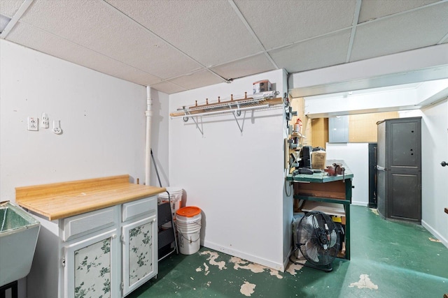 basement with a drop ceiling and electric panel