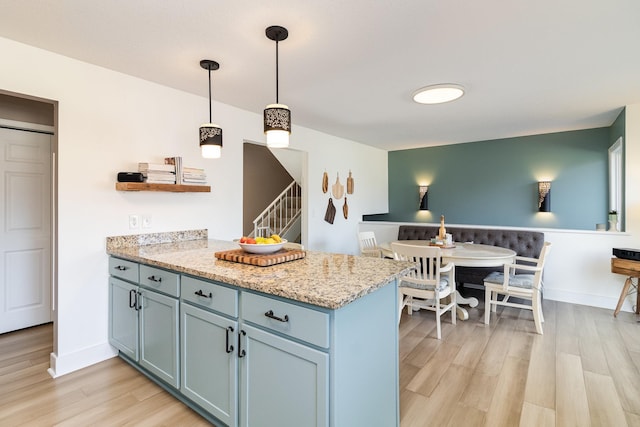 kitchen featuring baseboards, a peninsula, light wood-style flooring, and pendant lighting