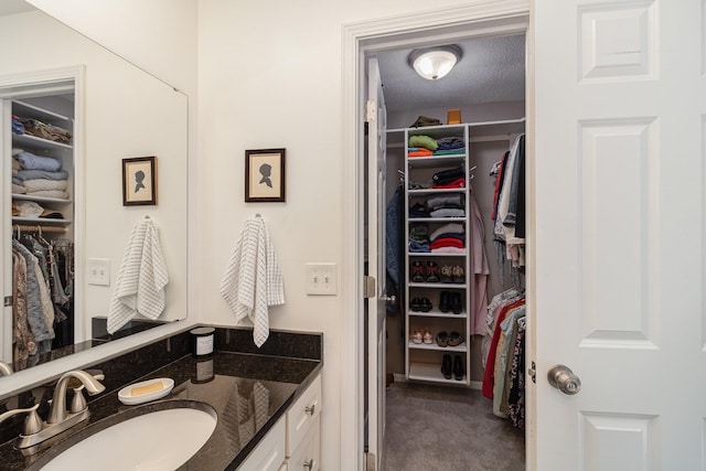 bathroom featuring a walk in closet, a textured ceiling, and vanity