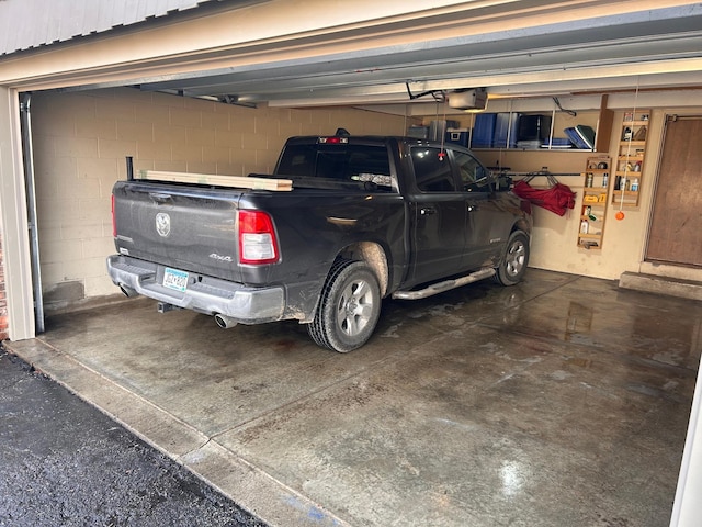 garage featuring concrete block wall and a garage door opener