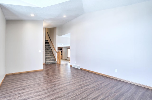 spare room featuring high vaulted ceiling and dark hardwood / wood-style flooring