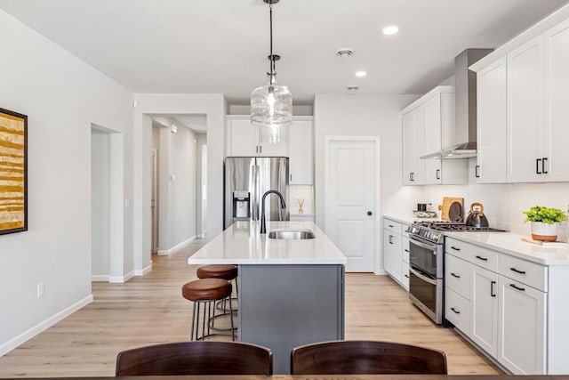10974 37th St N, Lake Elmo, MN 55042 - kitchen with wall chimney range hood, a breakfast bar area, appliances with stainless steel finishes, a sink, and light wood finished floors