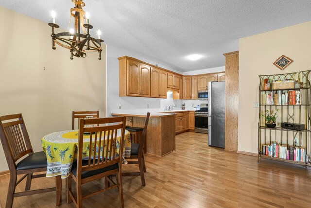 11030 Mississippi Blvd NW Unit 221, Coon Rapids, MN 55433 - kitchen with stainless steel appliances, a peninsula, light wood-style flooring, a chandelier, and brown cabinets