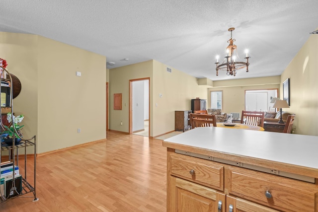 11030 Mississippi Blvd NW Unit 221, Coon Rapids, MN 55433 - kitchen featuring a chandelier, light wood-style flooring, open floor plan, light countertops, and a textured ceiling