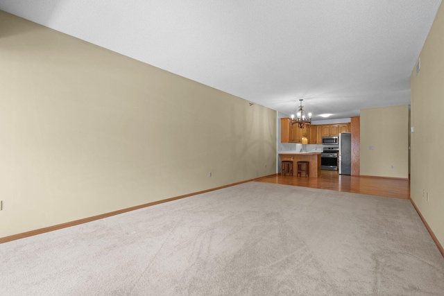 11030 Mississippi Blvd NW Unit 221, Coon Rapids, MN 55433 - unfurnished living room featuring a chandelier, light colored carpet, and baseboards