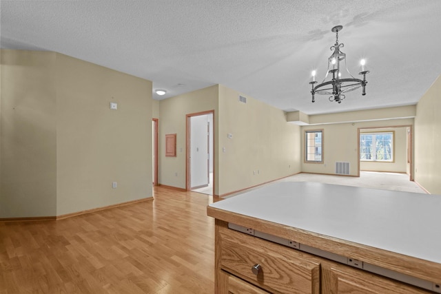 11030 Mississippi Blvd NW Unit 221, Coon Rapids, MN 55433 - unfurnished living room with a chandelier, light wood finished floors, a textured ceiling, and baseboards