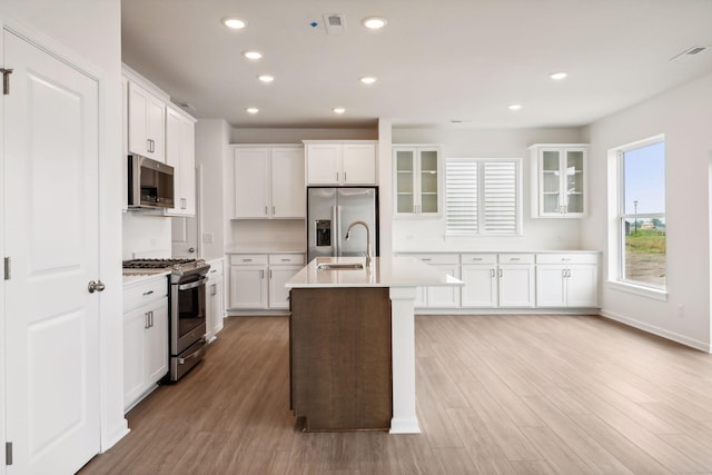 kitchen featuring stainless steel appliances, white cabinetry, and a kitchen island with sink