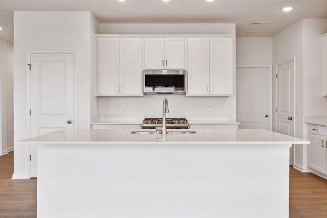 kitchen with white cabinetry and a center island with sink