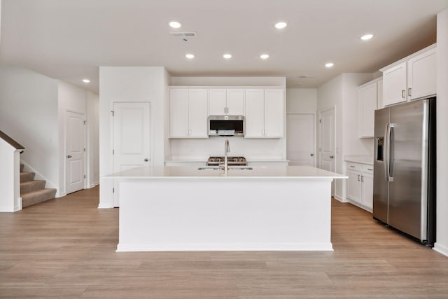 kitchen featuring light hardwood / wood-style floors, an island with sink, white cabinets, and appliances with stainless steel finishes