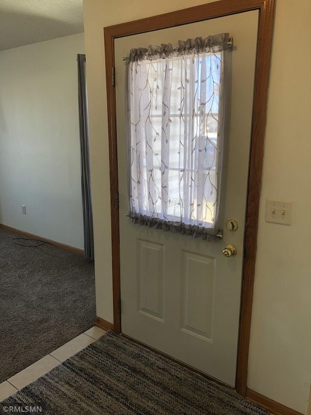 entryway with light carpet, baseboards, and light tile patterned flooring