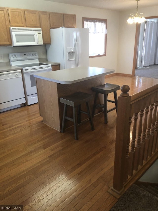 kitchen featuring dark wood-style floors, a notable chandelier, white appliances, and light countertops