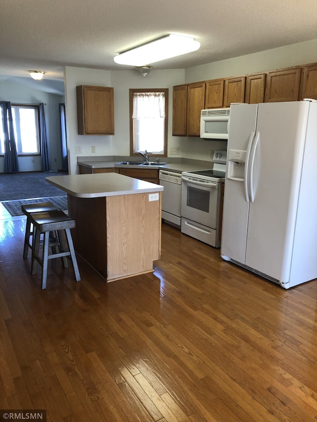 kitchen featuring white appliances, a healthy amount of sunlight, dark wood-style floors, and brown cabinets