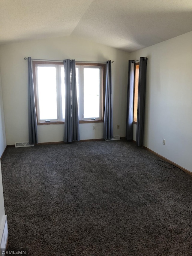 carpeted empty room featuring baseboards, visible vents, a textured ceiling, and lofted ceiling