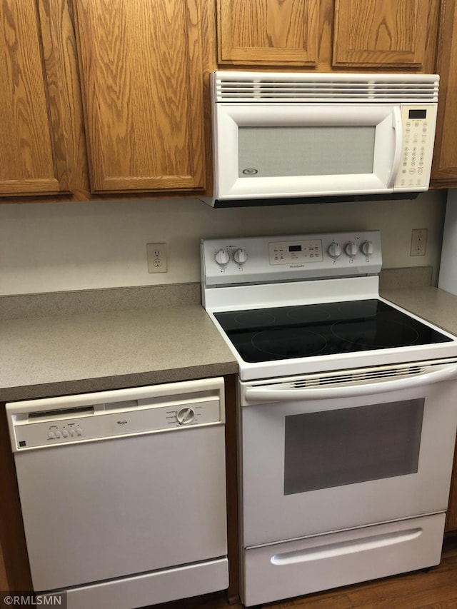 kitchen with brown cabinetry and white appliances