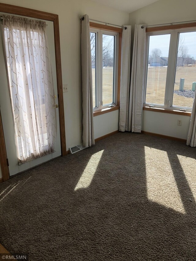 carpeted spare room with visible vents, baseboards, and vaulted ceiling