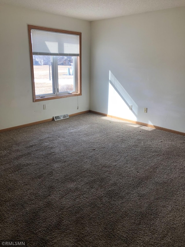 carpeted spare room with visible vents, a textured ceiling, and baseboards