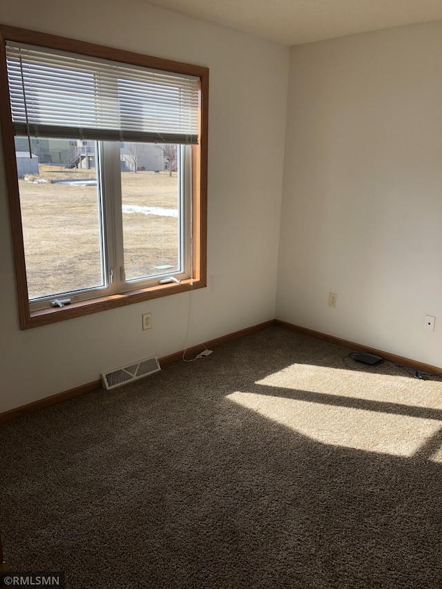 unfurnished room with plenty of natural light, baseboards, visible vents, and carpet floors