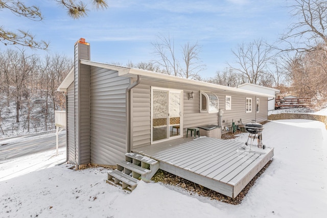 snow covered back of property with a deck