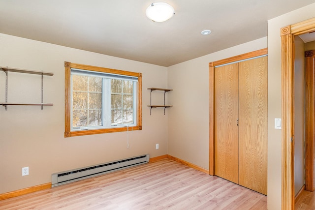 unfurnished bedroom featuring a baseboard radiator, light hardwood / wood-style floors, and a closet