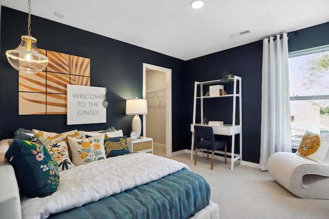 carpeted bedroom with a walk in closet