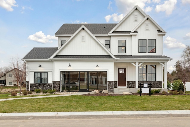 view of front of property featuring stone siding, board and batten siding, a front lawn, and a shingled roof