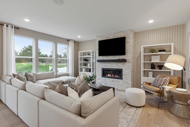 living room with recessed lighting, a stone fireplace, and wood finished floors