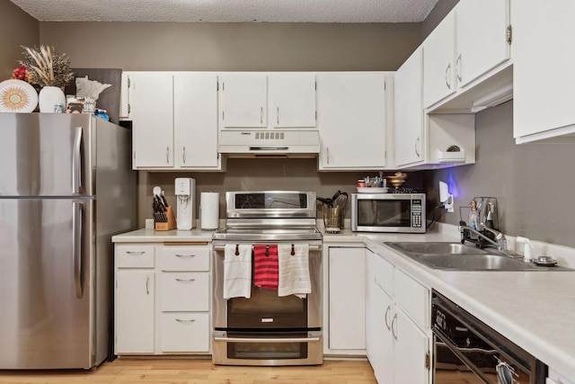 kitchen with appliances with stainless steel finishes, sink, white cabinets, and a textured ceiling