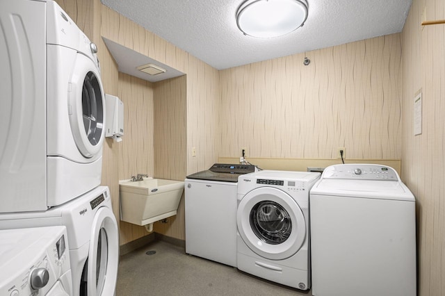 laundry area featuring washer and dryer, sink, a textured ceiling, and wood walls