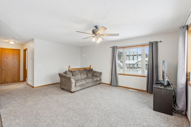 living room with ceiling fan, carpet floors, and a textured ceiling